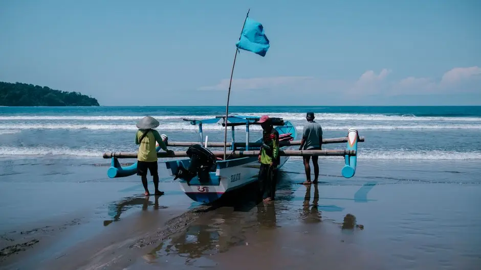 Pasir merah muda Pantai Pink di Labuan Bajo, NTT, dengan latar perahu nelayan dan langit biru